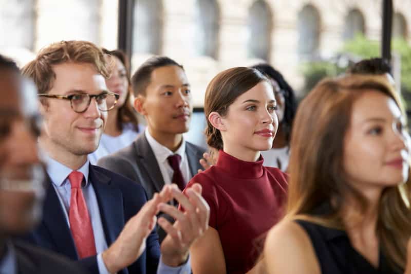 Publikum applauderer ved et forretningsseminar, tæt på